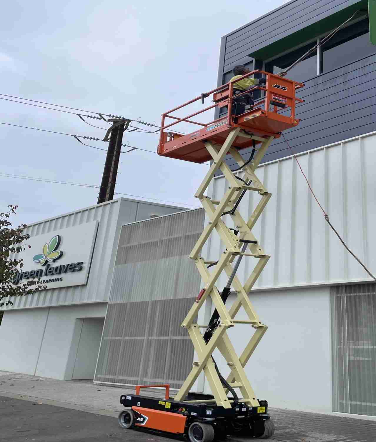 Adelaide-commercial-pressure-clean-case-study A person is using a scissor lift to pressure clean high windows at Green Leaves Early Learning Centre