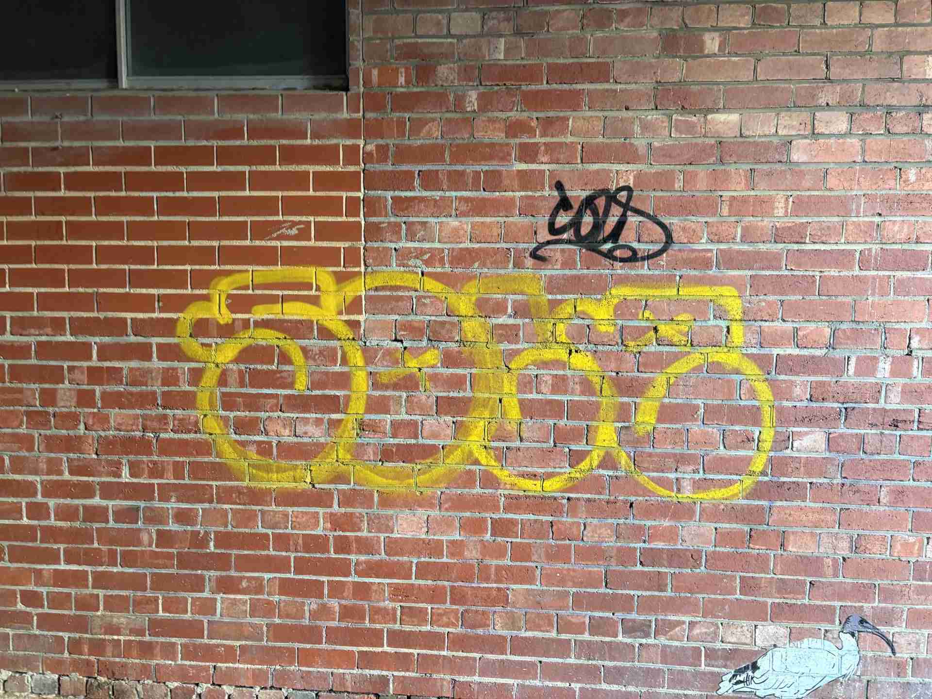 Graffiti-removal-Adelaide Yellow graffiti tag on a brick wall