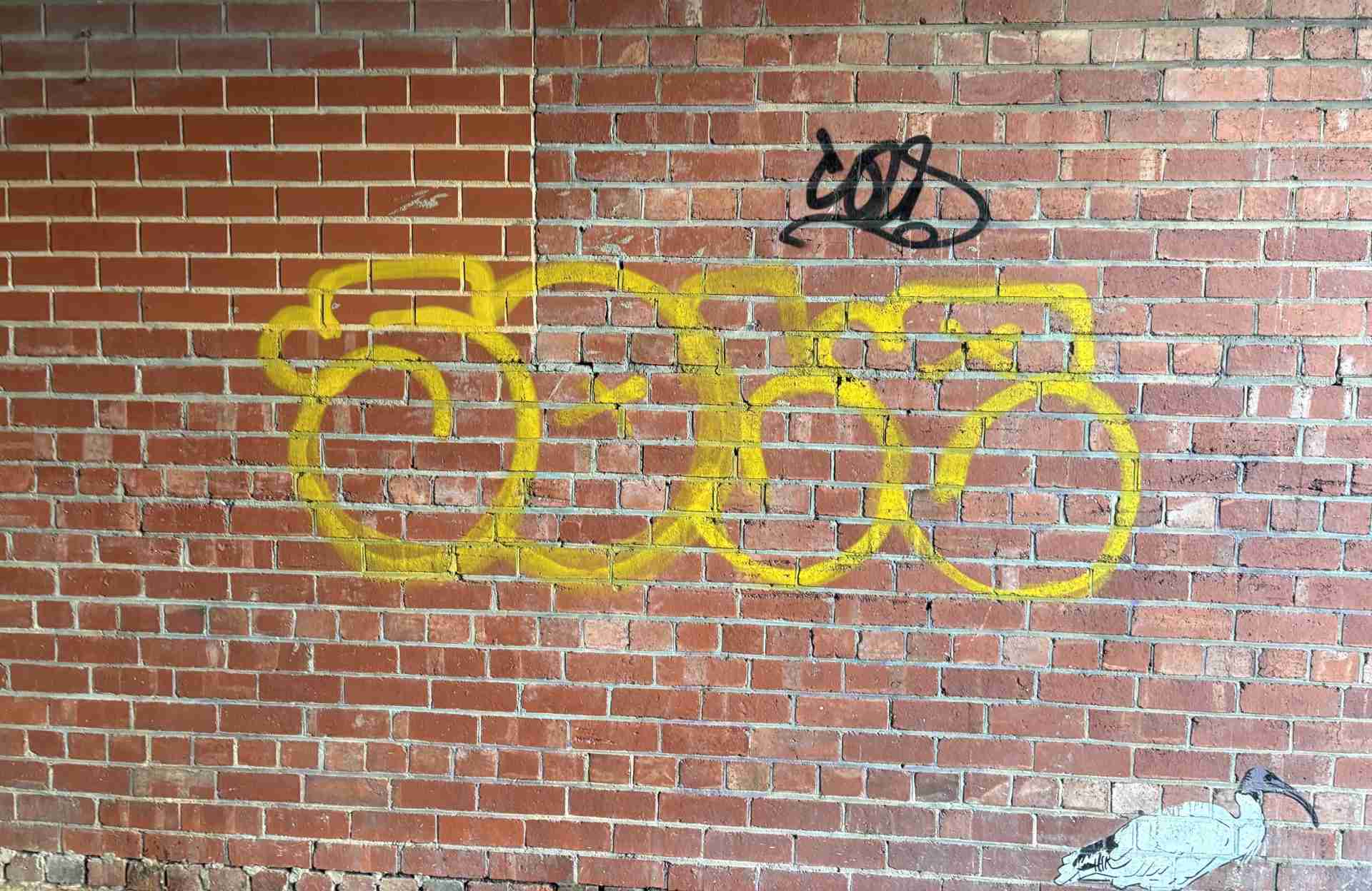 Yellow tag graffiti on a red brick wall